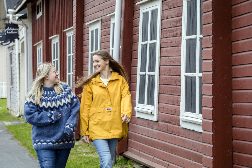 Kaksi naista kävelee Tornion kadulla. taustalla punainen hirsirakennus.